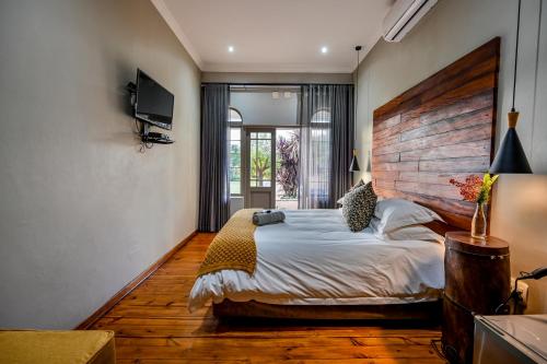 a bedroom with a large bed with a wooden headboard at Blue Rain Guest House in Bloemfontein
