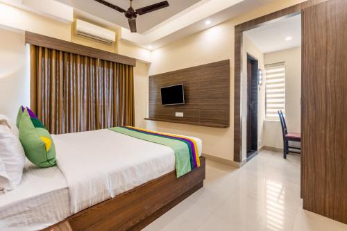 a bedroom with a bed and a flat screen tv at Treebo Sky City Grand, 5 Min From Mangalore Airport in Mangalore