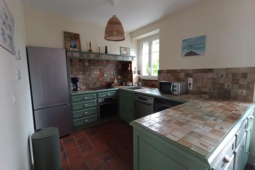 a kitchen with green cabinets and a counter top at Villa le Roche du Ris - 10-12 personnes in Baraize