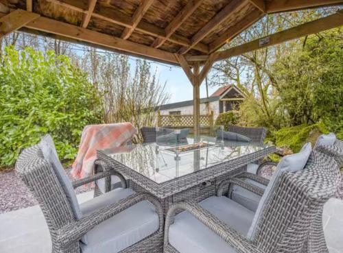 a patio with a glass table and chairs at Frondeg Bach in Tregaron