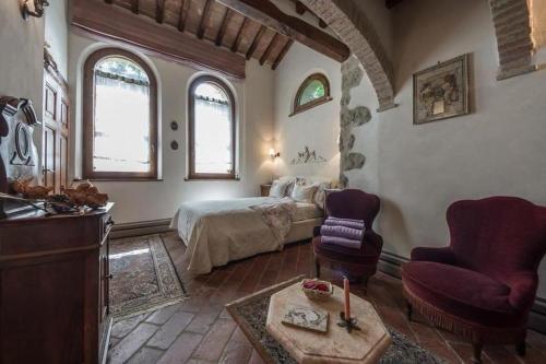 a bedroom with a bed and two chairs in a room at Il Casolare delle Fiabe in Casole dʼElsa