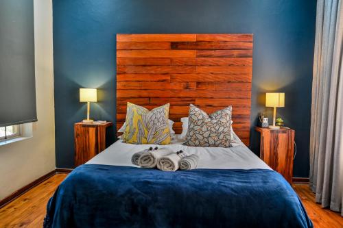 a bedroom with a large bed with a wooden headboard at Blue Rain Guest House in Bloemfontein