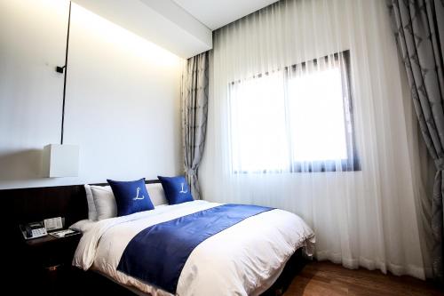 a bedroom with a large bed and a window at Lapis Hotel Namhae in Namhae
