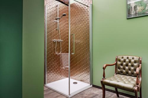 una doccia con porta in vetro accanto a una sedia di B&B CONVENT Begijnhof Herentals a Herentals