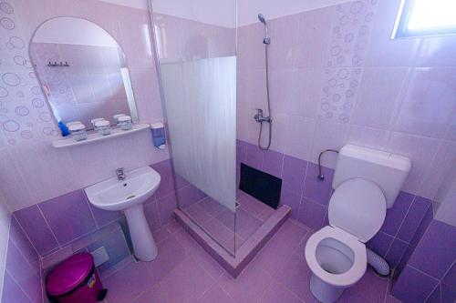 a purple bathroom with a toilet and a sink at Pensiunea Domneasca in Piteşti