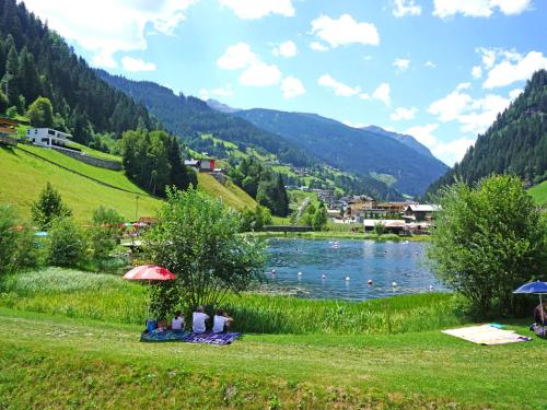 a group of people sitting under umbrellas near a lake at Apartment Hirsch by Interhome in See