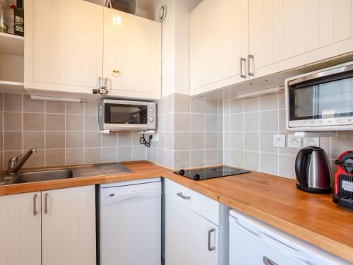 une cuisine avec des armoires blanches, un évier et un micro-ondes dans l'établissement Studio Ascot by Interhome, à Deauville