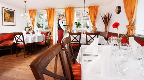 Eine Frau steht in einem Restaurant mit Tischen in der Unterkunft Landgasthof Löwen in Oberopfingen