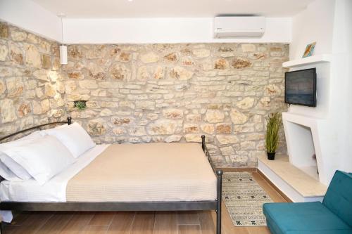 a bedroom with a bed and a stone wall at Captain theo apartment Annoula in Lefkímmi