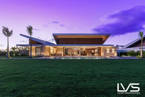 a modern house with a lawn in front of it at Zen Oasis Villa at Casa de Campo in La Romana