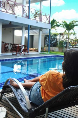 a woman sitting in a chair next to a swimming pool at Pousada Camocim Beach in Camocim