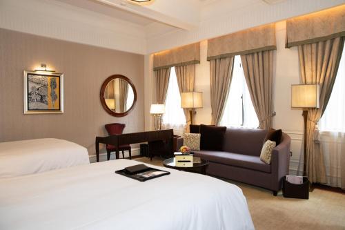 a hotel room with a bed and a couch and a mirror at Fairmont Peace Hotel on the Bund in Shanghai