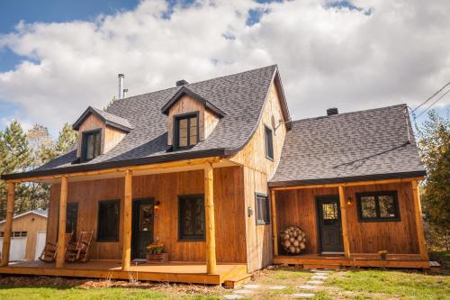 a wooden house with a gambrel roof at Au Chic Chalet des Chutes Chic Chalet in Sainte-Melanie
