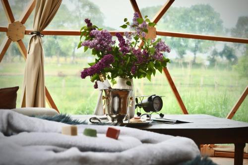 a vase of purple flowers on a table in front of a window at Parc Du Coq à l'Âne - Lodges Insolites in Saint-Georges-de-Rex