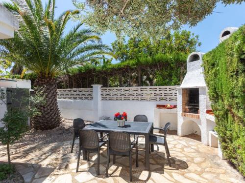 a patio with a table and chairs and a palm tree at Holiday Home Avellaner by Interhome in Miami Platja
