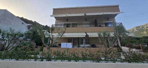 a building with a balcony with trees in front of it at Deluxe Apartmani Vila Pejovic Sutomore in Sutomore