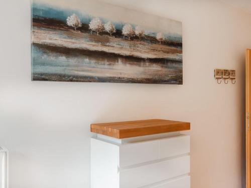 a painting hanging on a white wall with a wooden shelf at Holiday Home Rübezahl-3 by Interhome in Bad Hofgastein