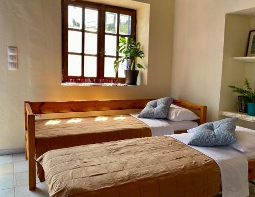 two beds in a room with a window at Lena & Louis in Andros