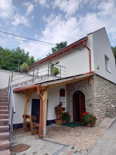 a white house with a staircase and a porch at Borház in Dédestapolcsány