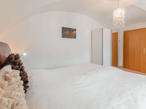 Un dormitorio con una gran cama blanca y una lámpara de araña. en Apartment Rübezahl-1 by Interhome, en Bad Hofgastein
