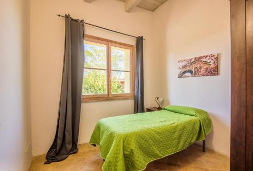 a bedroom with a green bed and a window at Chalet with common swimming-pool immersed in the Tuscan countryside in Trequanda