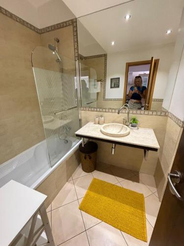 a man taking a picture of a bathroom with a sink and shower at Três palmeiras with pool in Portimão