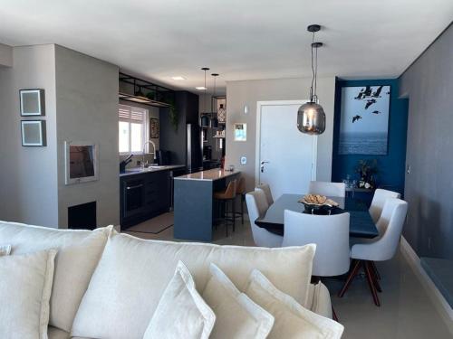 a living room with a white couch and a kitchen at Terra Brasilis Linda vista mar, completo, aconchegante, bem localizado in Balneário Camboriú