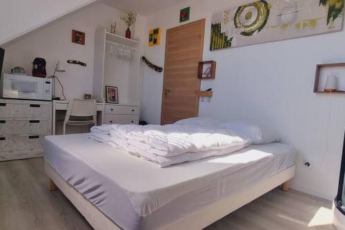 Cet appartement comprend une chambre avec un lit blanc et une cuisine. dans l'établissement l'Ecrin de l'Aa - La Salicorne, à Grand-Fort-Philippe