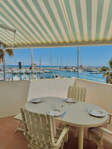une table et des chaises avec vue sur la marina dans l'établissement Superbe T2 avec vue sur le port et la mer avec parking privé 4RP221, au Barcarès