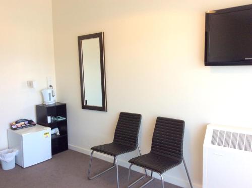 two black chairs in a room with a mirror at Fiordland Hotel in Te Anau