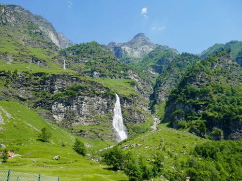 a waterfall in the mountains with green grass at Holiday Home Rustico Bel Panorama by Interhome in Malvaglia
