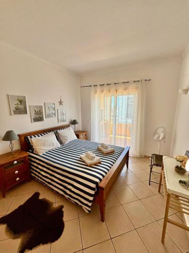 a bedroom with a bed with a blue and white comforter at Três palmeiras with pool in Portimão
