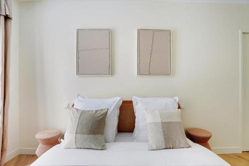 une chambre avec un lit avec des draps blancs et des oreillers dans l'établissement Suite BellesFeuilles - Terrasse, à Paris