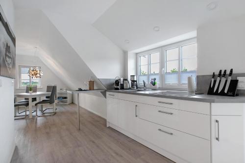 a white kitchen with a sink and a table at Käptn's Huus in Klanxbüll