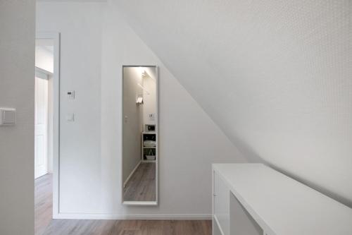 a white staircase with a mirror in a white room at Käptn's Huus in Klanxbüll