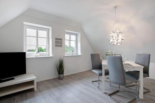 a dining room with a table and a tv at Käptn's Huus in Klanxbüll