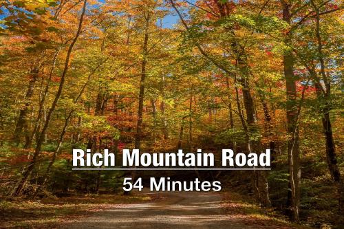 a road in the autumn forest with the words rich mountain road minutes at New Luxury Cabin with Stunning MountainVIEWS,HotTub, FirePit, FirePlace,2 KingBeds, 2 CoveredDecks,BBqGrill, ShuffleBoard and Pool Access in Sevierville