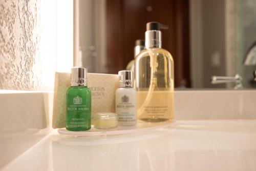 three bottles ofodorizers sitting on a bathroom sink at Hillsdale College Dow Hotel and Conference Center in Hillsdale