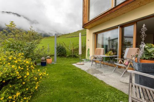 a garden with a table and chairs next to a house at Chasa Arpiglia in Guarda