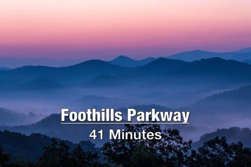 a view of a mountain range with the text foothills parkway minutes at New Luxury Cabin with Stunning MountainVIEWS,HotTub, FirePit, FirePlace,2 KingBeds, 2 CoveredDecks,BBqGrill, ShuffleBoard and Pool Access in Sevierville