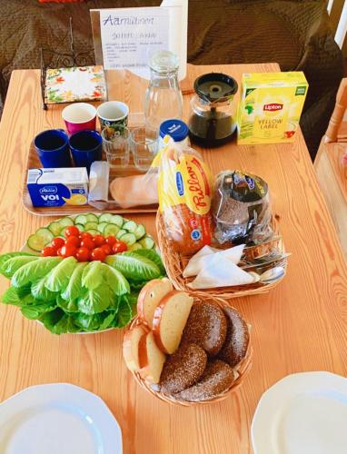 a table with a basket of bread and vegetables on it at Ollinpolun matkakoti in Sulkava