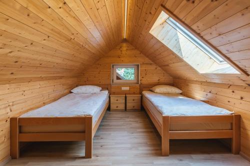 two beds in a log cabin with a window at Pogacar Apartments in Bled