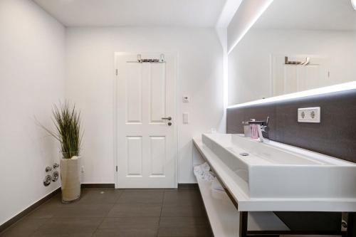 a white bathroom with a sink and a mirror at Käptn's Huus in Klanxbüll