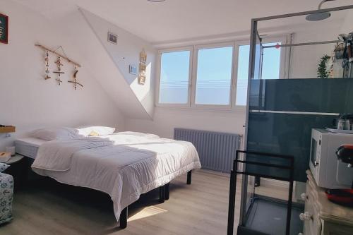 una camera da letto con un letto in una stanza con finestre di l'Ecrin de l'Aa - Les Mouettes a Grand-Fort-Philippe