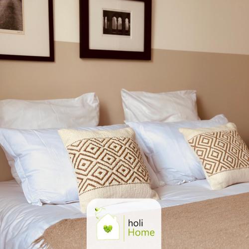 un lit avec des oreillers blancs et un panneau indiquant « maison chaude » dans l'établissement H5 Bel appartement proximité gare et centre-ville, à Vitré