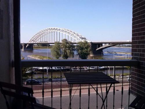 a view of a bridge from a balcony with a bench at Hotel Courage Nijmegen in Nijmegen