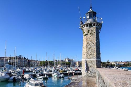 a lighthouse in a marina with boats in the water at Gioiella, pool & lake in Desenzano del Garda