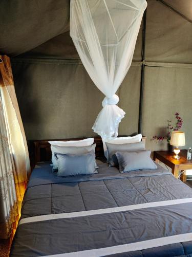 a bedroom with a bed with curtains and pillows at Harmony Haven, Udawalawe, Sri Lanka in Udawalawe