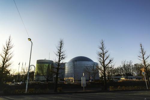 a large glass building with a bus in front of it at Base605 in Kurume