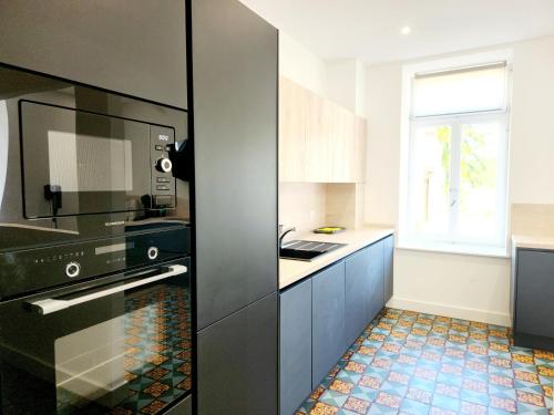 a kitchen with a black refrigerator and a window at Le Jardin d'Eden in Ay-sur-Moselle